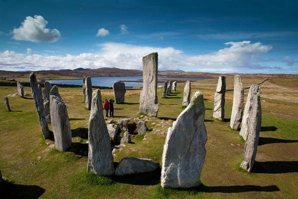 Die Calanais Standing Stones werden von einem Besucherpaar auf der Insel Lewis an einem wunderschönen Tag bewundert