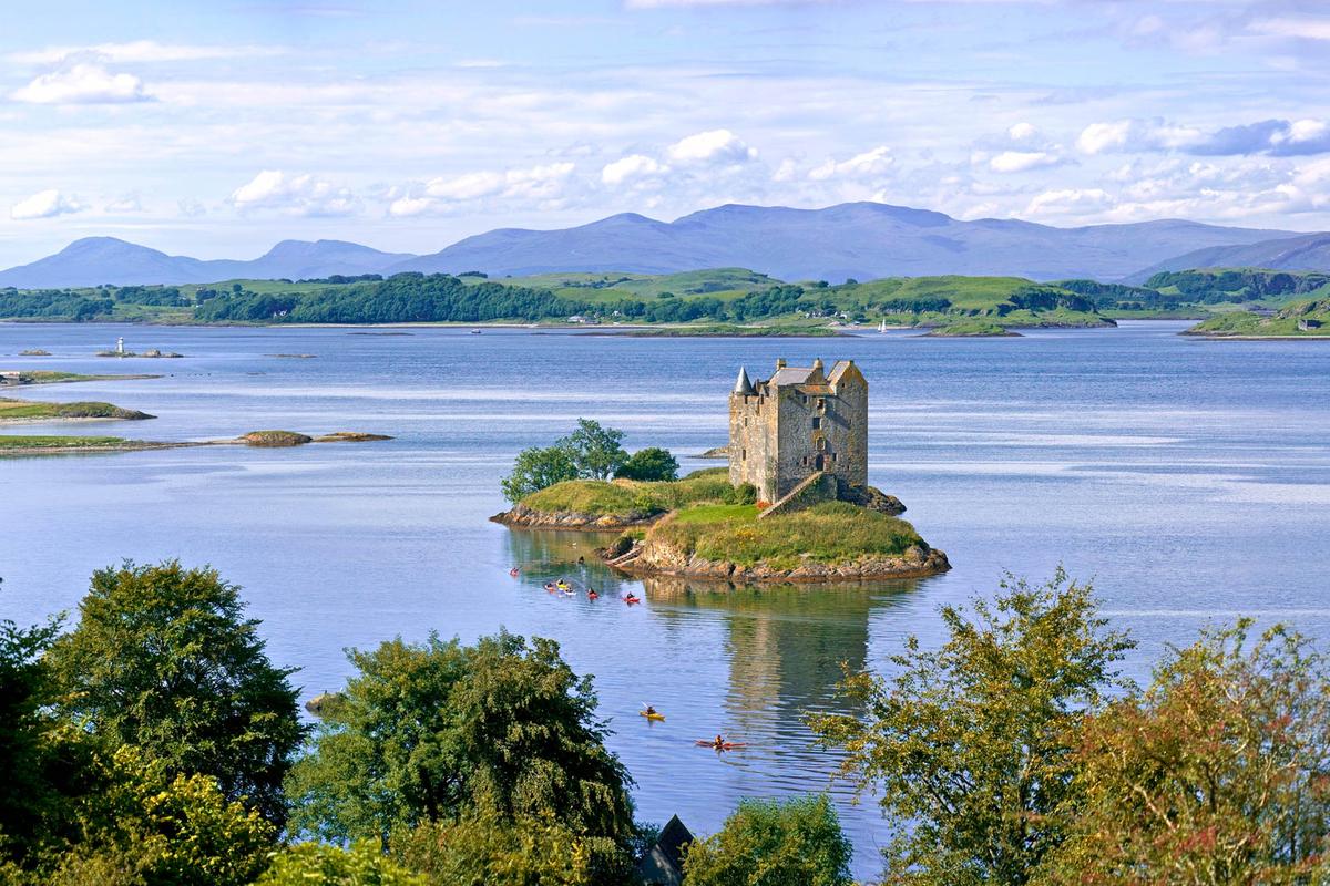 Castle Stalker and Loch Laich surrounding it, with the Isle of Lismore in the background