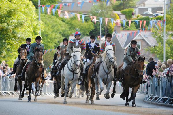 Paardenraces op straat tijdens de Selkirk Common Riding, bekeken door de menigte