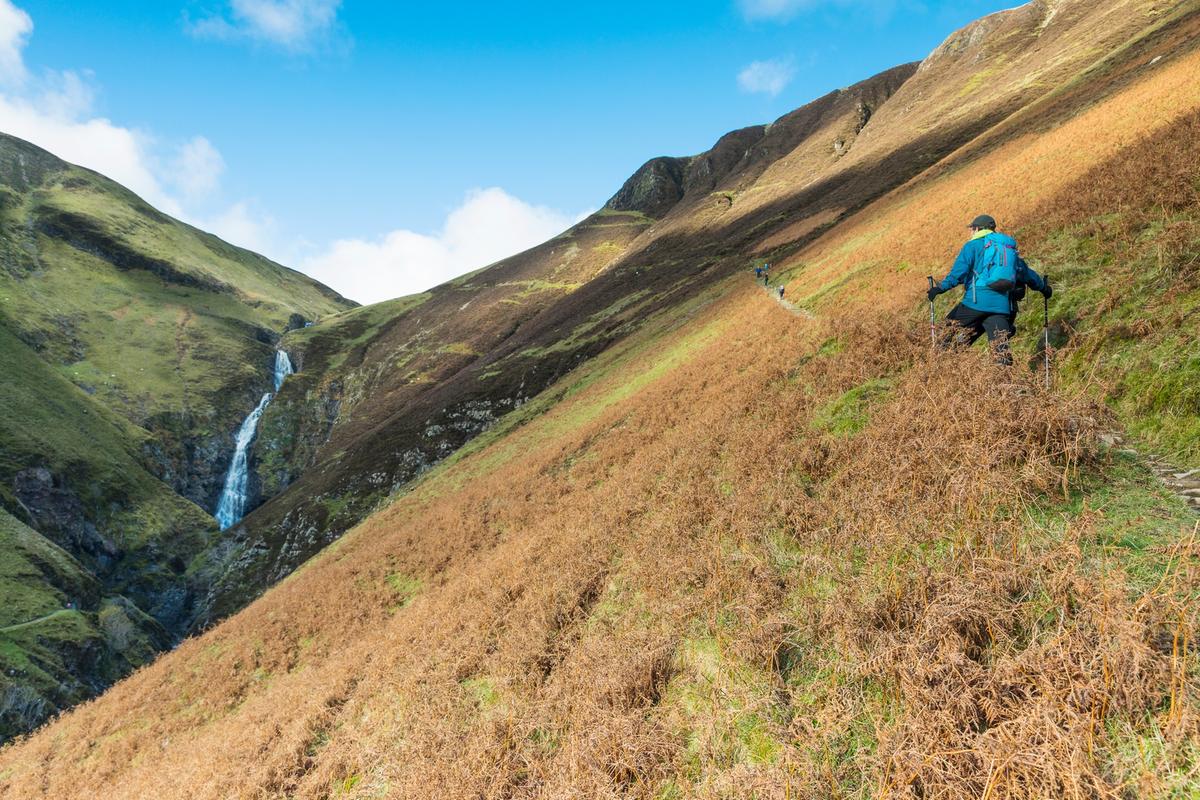 Walkers climb the hillside by Grey Mare's Tail, one of the UK's highest waterfalls, in the Moffat Water Valley, Dumfries & Galloway