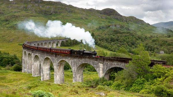 ll famoso treno a vapore The Jacobite attraversa il viadotto di Glenfinnan vicino al Loch Shiel, Lochaber, Highlands